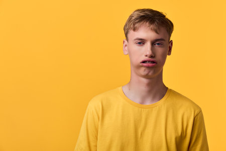 Young man wearing a yellow tshirt stands against a bright yellow background, neutral expression, casual studio style with bold color and clean simple compositionの写真素材