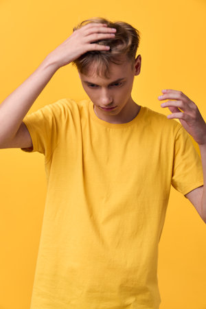 Male model in a yellow t shirt touches his head with a thoughtful look against a bright yellow...