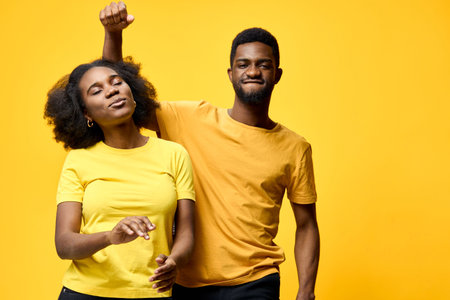 Happy diverse couple dancing joyfully with vibrant yellow background, portraying love and connection through vibrant colors and festive energyの写真素材
