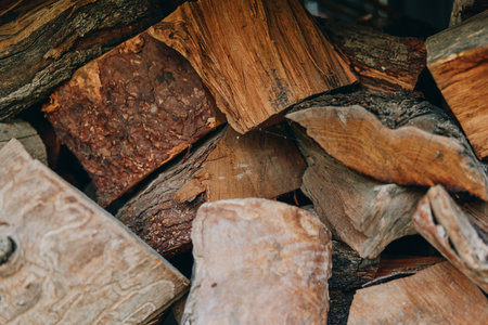 Firewood chopped wood stacked logs closeup with timber and bark texture, rustic woodpile for cabin lifestyle, flannel shirt homeowner stacking pieces for cozy winter heating and hearth.の写真素材