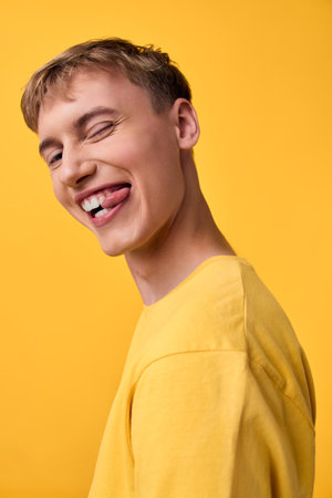 Smiling man, yellow shirt, funny grin, crooked teeth, playful expression, studio scene, bright backdrop, energetic mood, bold color, candid and lighthearted moment in a controlled settingの写真素材