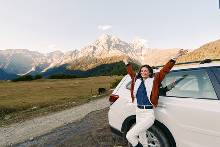 Woman car mountains travel nature road happy adventure with smiling female leaning on white SUV at mountain meadow, scenic landscape, sunlight and freedom during outdoor trip and journeyの写真素材