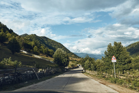 Road mountain landscape rural trees sky clouds nature, peaceful scene authenticity inclusivityの写真素材