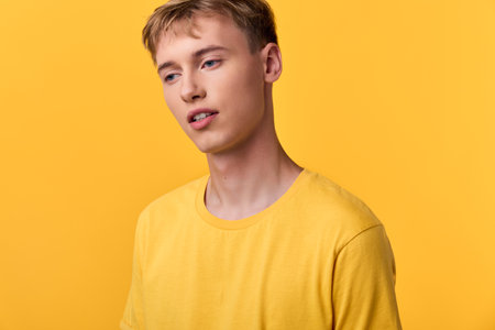 Young man in a bright yellow shirt against a solid yellow backdrop, studio shot with a minimalist...