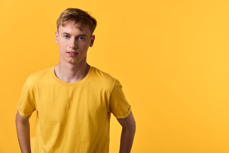 Man, young, yellow shirt, studio model pose against bold background, casual apparel, fashion, cheerful confidence, clean simple lines, minimalist vibe, bright lightingの写真素材