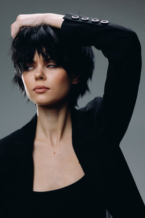 Stylish woman with short black hair posing in black jacket, modern fashion, confident expression,...