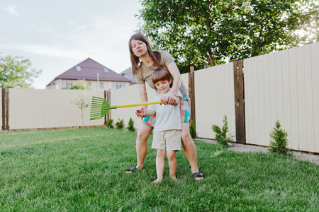 Active woman gardening with her son, enjoying a sunny day outdoors. A fun and playful atmosphere enhances the joy of family time in the garden.の写真素材