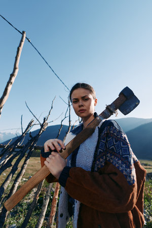 Woman with axe by fence in mountains countryside wood outdoor rural scene, young girl portrait...
