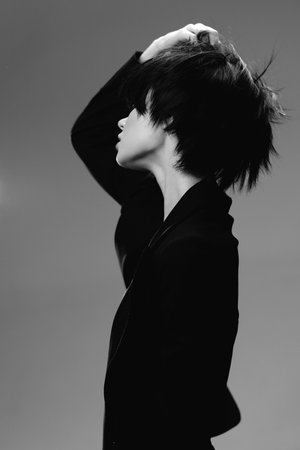 Black and white portrait of a woman with short hair touching her head in a thoughtful pose.の写真素材