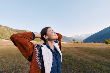 Woman in nature among mountains and meadow, portrait outdoors to relax wearing a warm sweater, eyes...