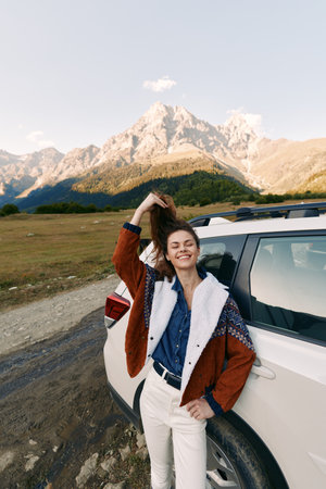 woman car mountains travel smile road nature adventure portrait of a happy female by an SUV, wearing casual jacket and denim, standing on a scenic roadside enjoying outdoor freedom.の写真素材