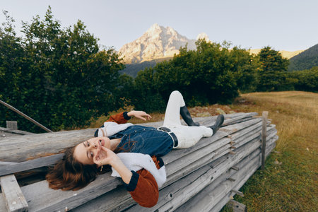 Woman relaxation on wooden fence in mountain meadow outdoors, portrait of casual young female lying...