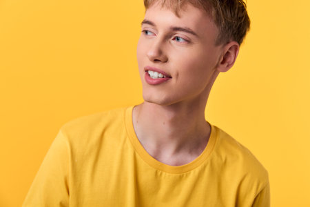 Man with a bright smile wearing a yellow shirt against a vibrant yellow backdrop, studio style for cheerful fashion, lifestyle or summer conceptの写真素材