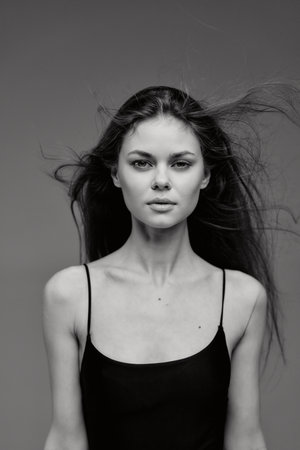 Black and white portrait of a young woman with flowing hair wearing a black tank topの写真素材