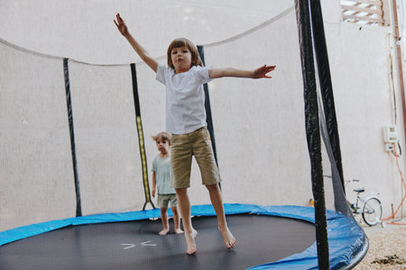 Happy children playing on a trampoline, enjoying their time outdoors with energetic jumps and laughter in a sunny atmosphere.の写真素材