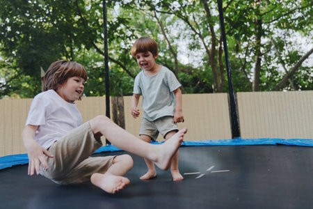 Happy boys playing on a trampoline outdoors, enjoying a sunny day with laughter and joy. Their playful spirits shine through in this delightful scene.の写真素材