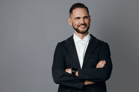 A confident business professional stands with arms crossed against a plain colored backdrop, projecting authority and approachability. The isolated background highlights leadership and expertiseの写真素材