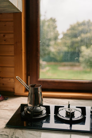 Cozy kitchen scene with a pot on a gas burner, sleek stove, and a bright window overlooking a green garden, inviting warm home cooking momentsの写真素材