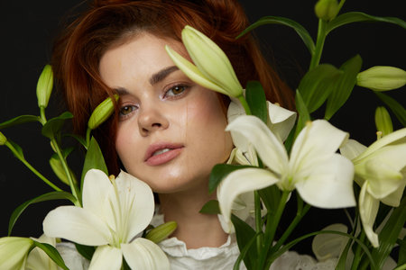 A young woman with red hair surrounded by white lilies, showcasing elegance and natural beauty,...