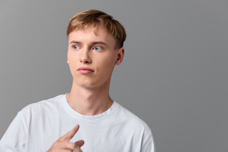 Man, thinking, thoughtful expression with sideways gaze in a casual white shirt, studio shot,...