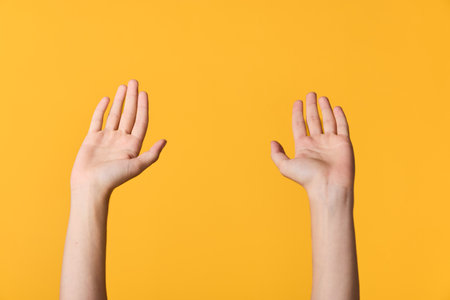 Hands raised against a bright yellow background, capturing a simple gesture of attention and openness. Minimalist concept suitable for communication, collaboration, safety, energy, or celebration inの写真素材