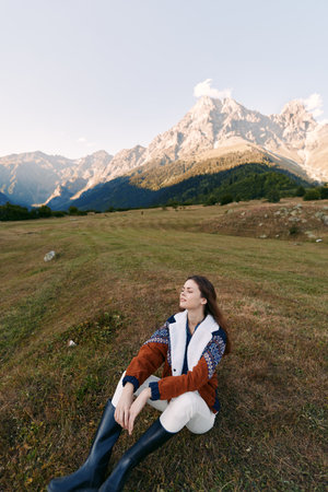 woman sitting on meadow in mountain landscape, nature scene with relaxed pose and closed eyes,...