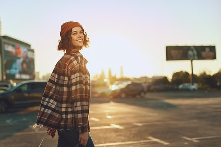 woman smiling urban walking beanie plaid sunlight candid lifestyle happiness authenticity golden...