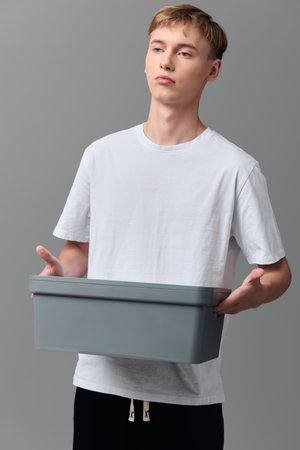Man holding a gray box for delivery, simple studio scene focused on ecommerce packaging, shipping...
