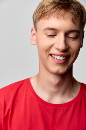 Smiling man wearing a red shirt closeup of happiness and warmth with a relaxed casual style soft lighting and cheerful mood in a simple studio settingの写真素材