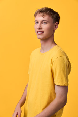 Yellow themed studio shot of a smiling man in a yellow t shirt, standing against a vivid yellow background, casual pose, clean lighting, cheerful mood, simple fashion image without brandingの写真素材
