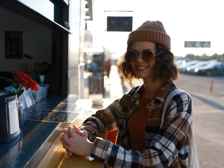 woman smile outdoor cafe beanie sunglasses candid urban portrait capturing authenticity and candid lifestyle with golden hour glow, mindful living vibe and emotional storytelling in cityの写真素材