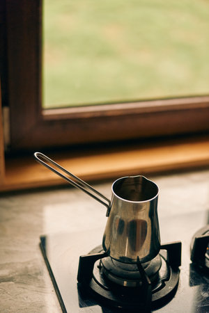Stove burner closeup with a metal kettle on a gas hob, silver steel surface reflecting light, capturing domestic cooking and kitchen use, showcasing daily use.の写真素材