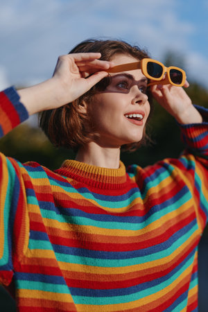 Woman, young woman, striped sweater, sunglasses, smiling, outdoor, portrait, short hair â Young woman in a colorful striped knit and yellow sunglasses looking up and smiling in a sunlit park, casualの写真素材