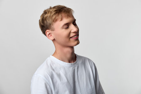 Smiling man in a white shirt in a studio setting, casual and relaxed, showcasing natural happiness...