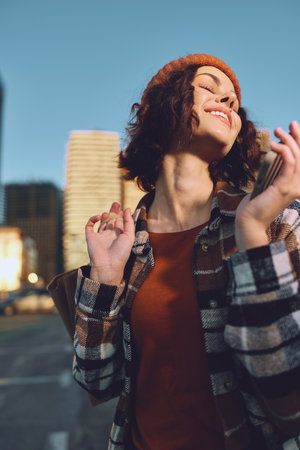 woman portrait smile city candid authenticity lifestyle golden hour: young woman in beret and plaid coat enjoying golden hour glow, candid lifestyle moment of mindful living and emotionalの写真素材