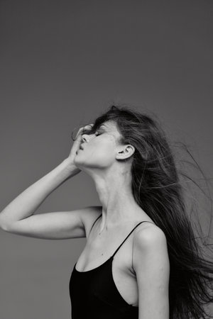 Black and white profile of a woman with long hair posing thoughtfully with closed eyes and delicate...
