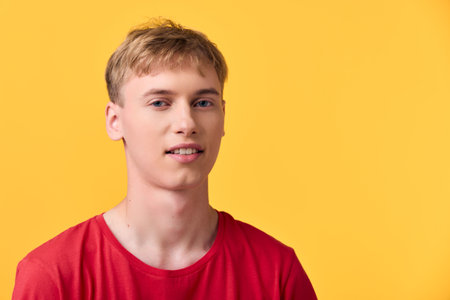 Man wearing a red t shirt against a bright yellow background, studio lighting, casual style, close up, confident expression, clean lifestyle vibe suitable for stock, fashion or advertising imageryの写真素材