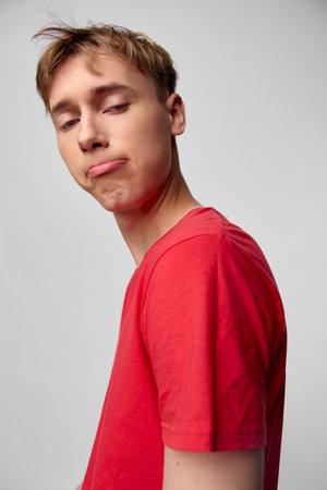 Young man with a silly face in a red shirt, casual style and playful mood, expressive pose for...