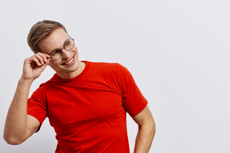 smiling young man wear red t-shirt glasses look aside isolated plain white background casual style positive emotions concept digital nomadの写真素材