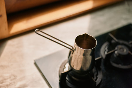 Coffee moka pot on a stove in a warm kitchen, metal surface gleaming as steam rises, capturing a cozy espresso ritual and everyday kitchen momentの写真素材