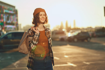 woman shopping with beanie and smile in urban sunset scene, candid lifestyle portrait capturing authenticity and golden hour glow, mindful living vibe and emotional storytelling momentの写真素材