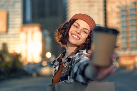 woman smile coffee urban candid lifestyle portrait at golden hour offering takeaway cup and shopping bag, authenticity and emotional storytelling with mindful living and warm golden hour glowの写真素材