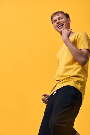 Joyful motion, energetic pose, yellow shirt, orange backdrop, cheerful vibe, dynamic expression capture a lively moment of casual fashion and self confidence in a studio setting, highlighting color,の写真素材