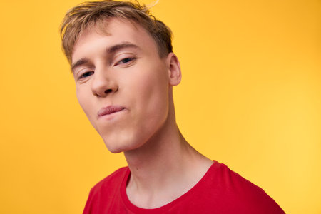 Close up of a man in a red shirt against a vibrant yellow backdrop, neutral expression, studio lighting, bold color contrast, modern style with clean, minimal compositionの写真素材