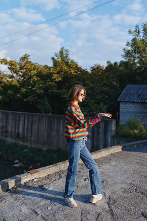 woman striped sweater jeans sunglasses rooftop walking casual outfit young adult smiling outdoors in...