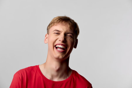 Smiling man in a red shirt bursts with laughter, capturing a moment of pure happiness and joyful energy, casual mood, expressive face and confident attitudeの写真素材