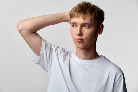 Man with puzzled expression, hand on head, casual white tee, studio lighting, conveying confusion...