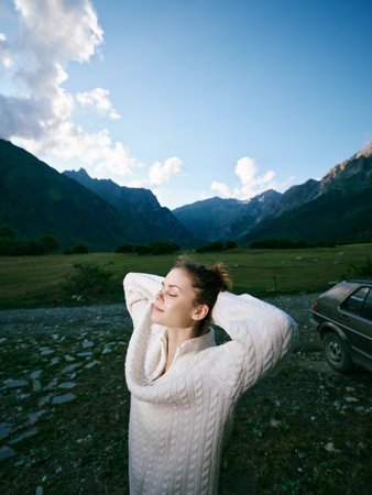 Mountain valley scenery with a relaxed woman in a cozy knit sweater, arms behind her head, enjoying...