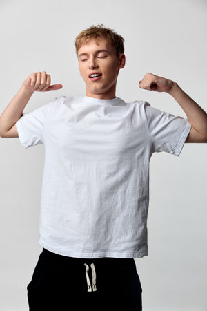 Casual male in white t shirt flexing arms to show confidence and casual strength in a clean studio...