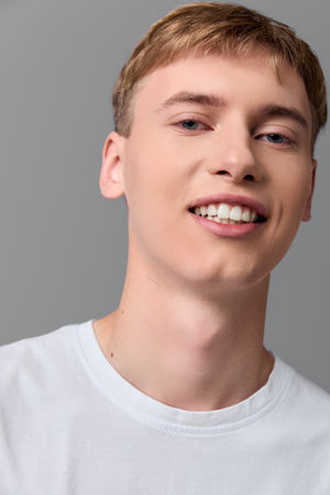 Man smiling in a white t shirt, studio setting, clean background, friendly and approachable look, ideal for lifestyle, branding and marketing campaignsの写真素材